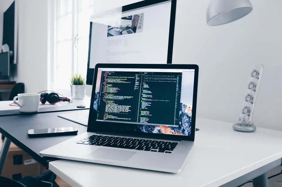 Laptop showing application code on a developer's desk